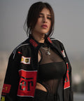 Woman wearing a black and red ferrari jacket with various logos 