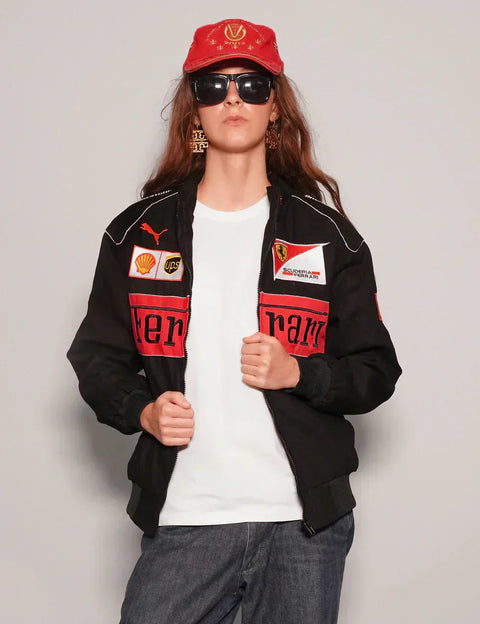 Person wearing a Women Black Ferrari Racing Jacket with Ferrari logos and a red cap on a plain background