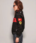 Person wearing a black jacket with Formula 1 logos on a plain background