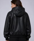 Person wearing a black leather bomber jacket on a plain background