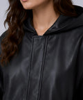 Close-up of a person wearing a black hooded jacket with a plain background