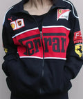 Black, red, and white Ferrari tracksuit jacket with various logos on a plain background