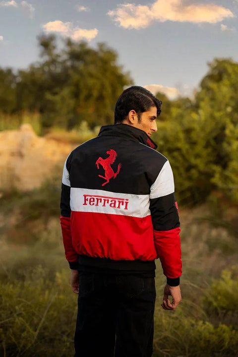 Person wearing a Ferrari jacket in an outdoor setting with trees and sky.